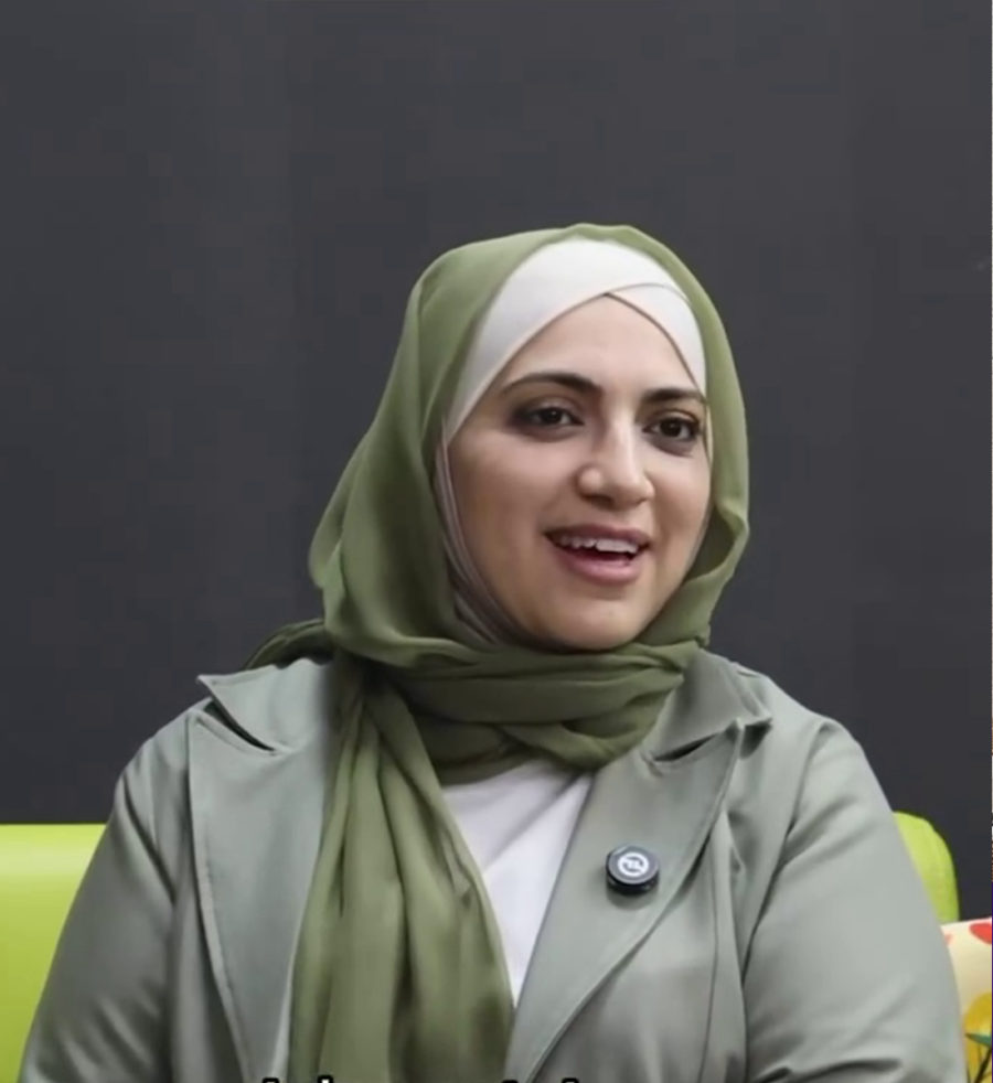 Heba Abou-Eid, in a green hijab and sage trench coat, smiling.