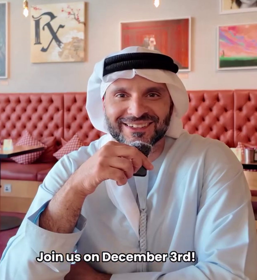 Mohamed Al Zarooni, Emirati singer-songwriter, smiling at a café table. On-screen caption: Join us on December 3rd!